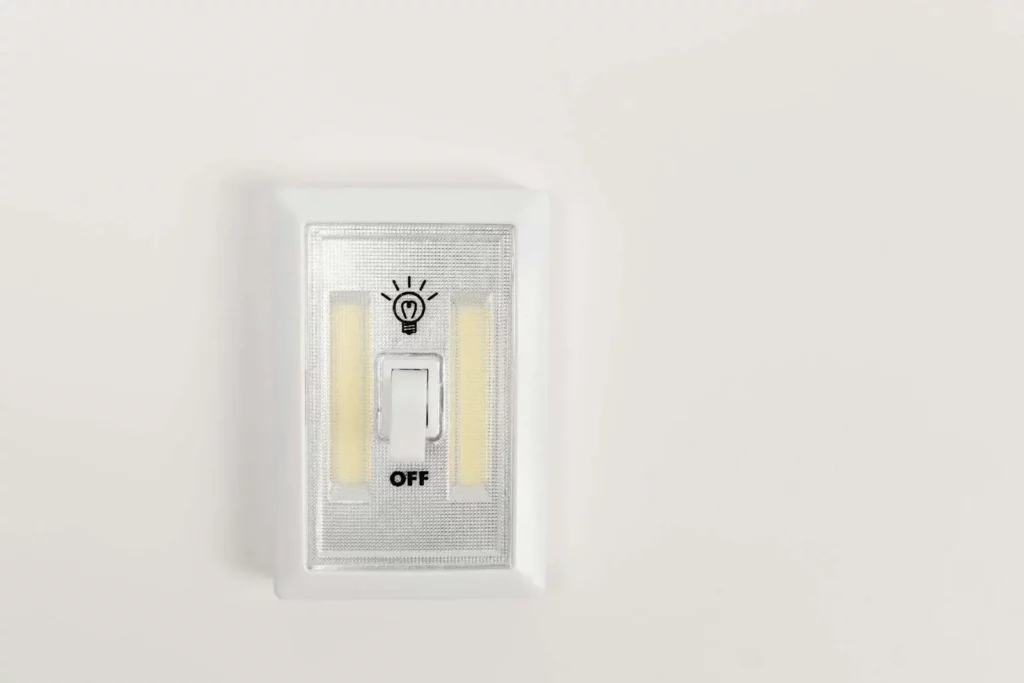Minimalist light switch turned off on a plain white wall, offering ample copy space.
