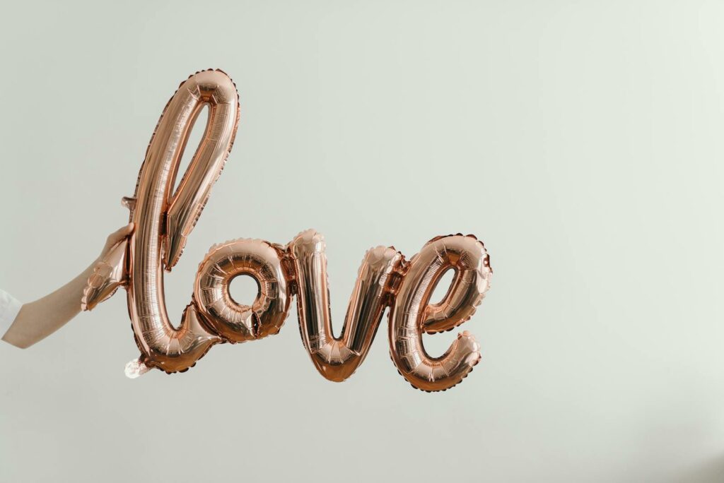 Elegant rose gold balloon spelling 'love' on a soft background, perfect for Valentine's Day themes.