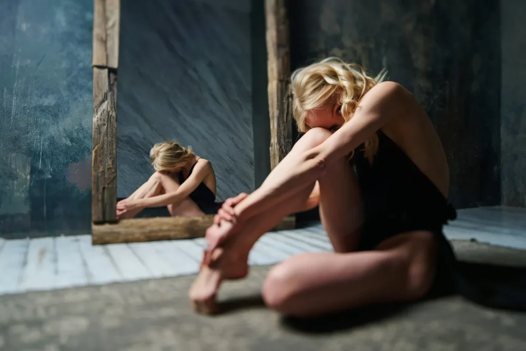 a woman sitting on the floor in front of a mirror